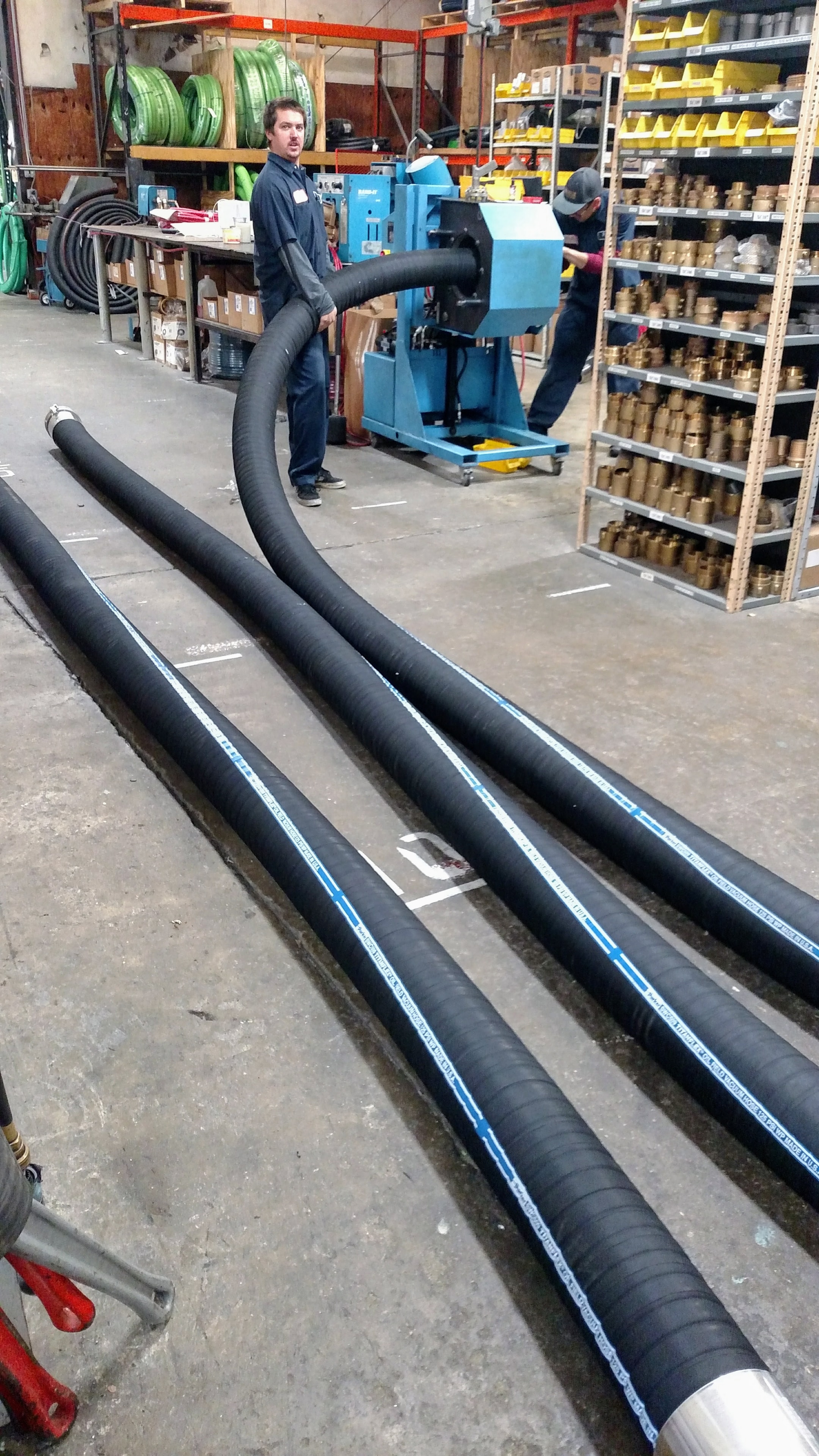 B&B Hose shop team fabricating large industrial hose assemblies on the crimping press