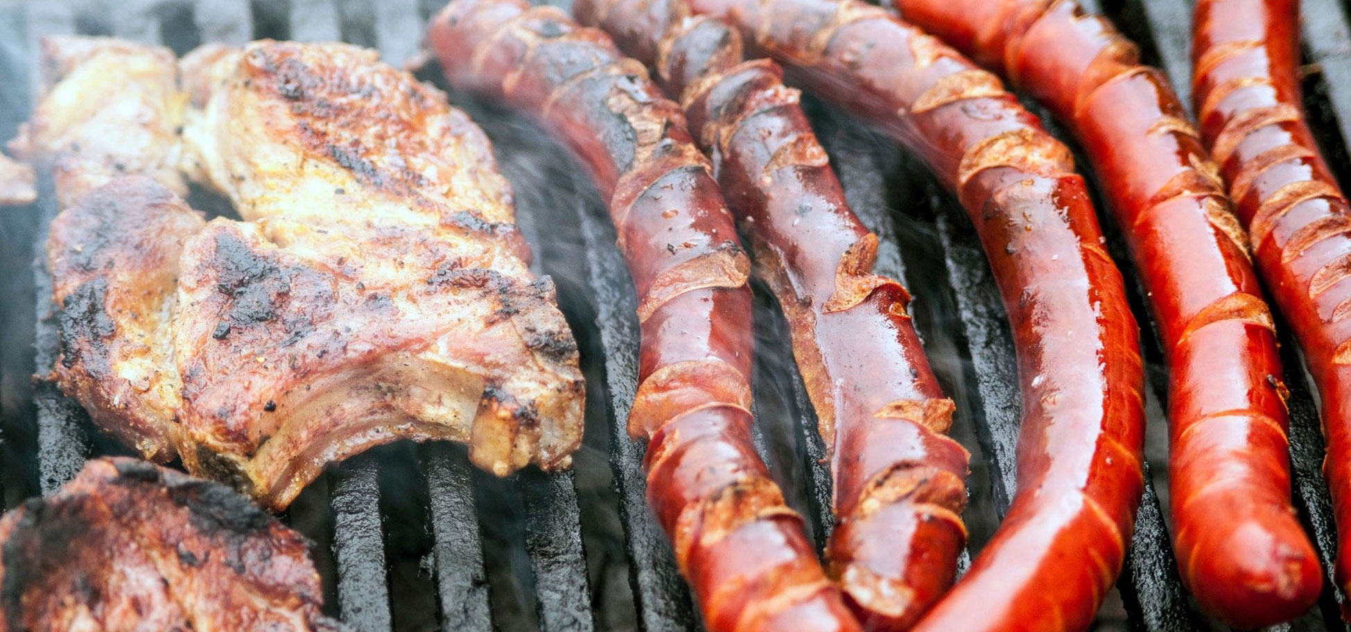 A grill with meat and sausage on it.